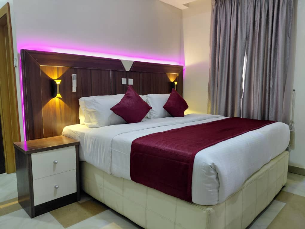 A guest bedroom dressed with a burgundy runner and bedside sconces